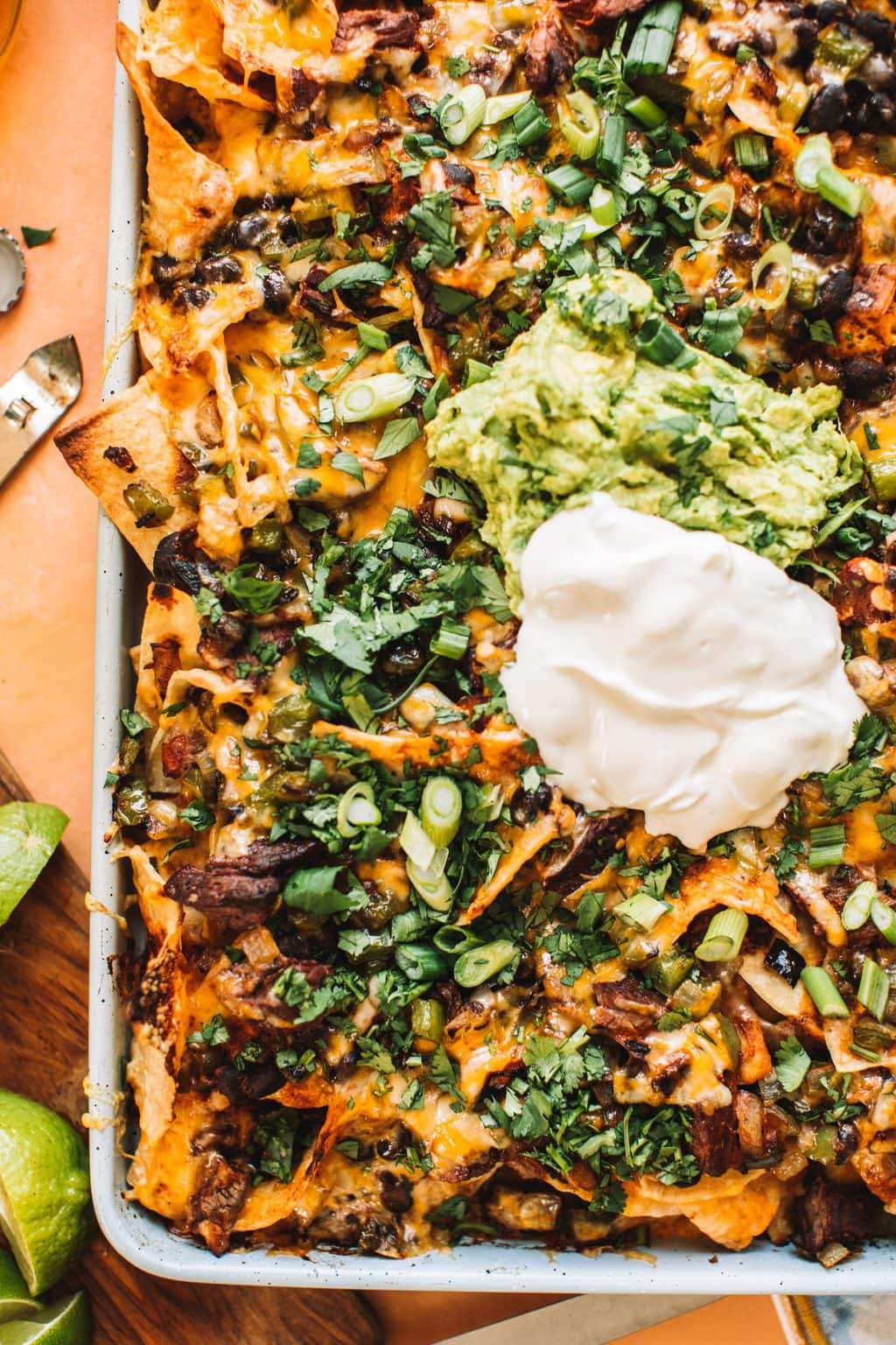 A corner platter of nachos topped with sour cream and guacamole.