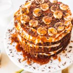 Top shot of cake with caramel and bananas on top, sitting on cake stand.