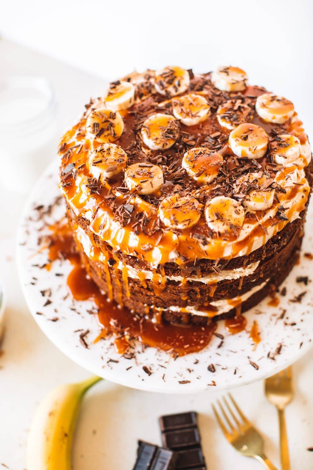 Top shot of cake with caramel and bananas on top, sitting on cake stand.