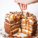 Woman putting fork into banana caramel cake with slices cut out.