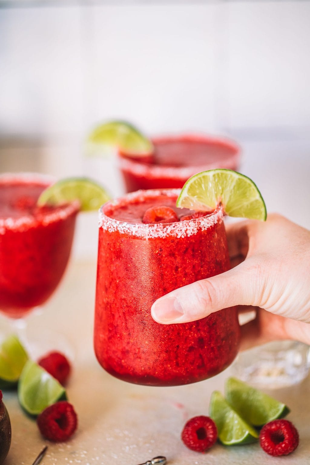 Holding a frozen raspberry margarita with a salted rim. 