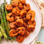 Top shot of cooked shrimp and asparagus on round plate.