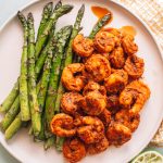 Top shot of cooked shrimp and asparagus on round plate.