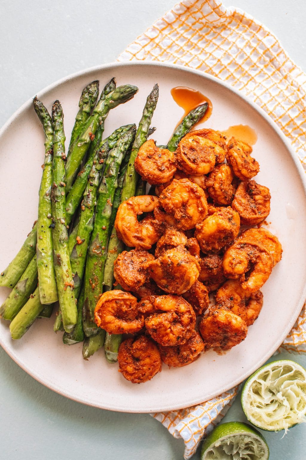 Top shot of cooked shrimp and asparagus on round plate.