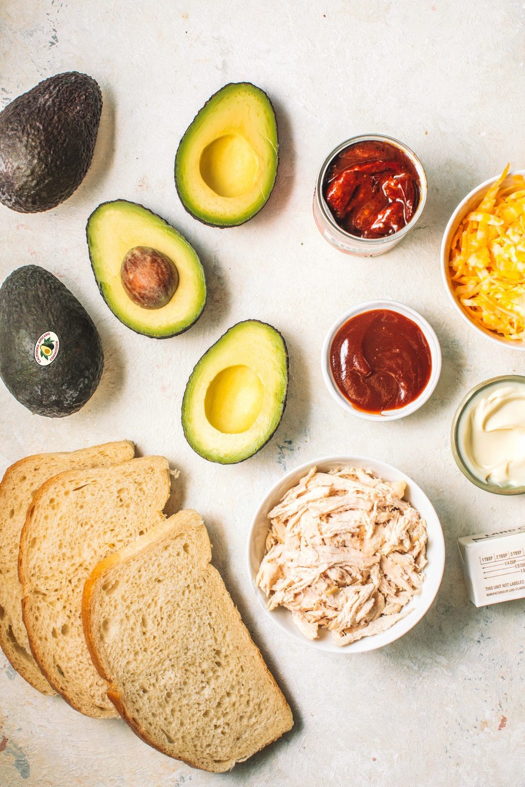 Avocados, sourdough bread slices, pulled chicken, bbq sauce, chipotle in adobo sauce, shredded cheese, mayonnaise and butter.