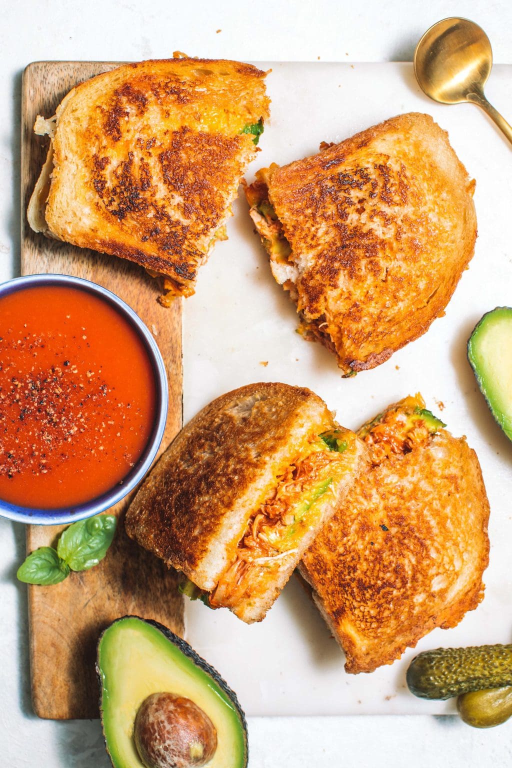 Chipotle chicken avocado melt slices served with tomato soup and pickles. 