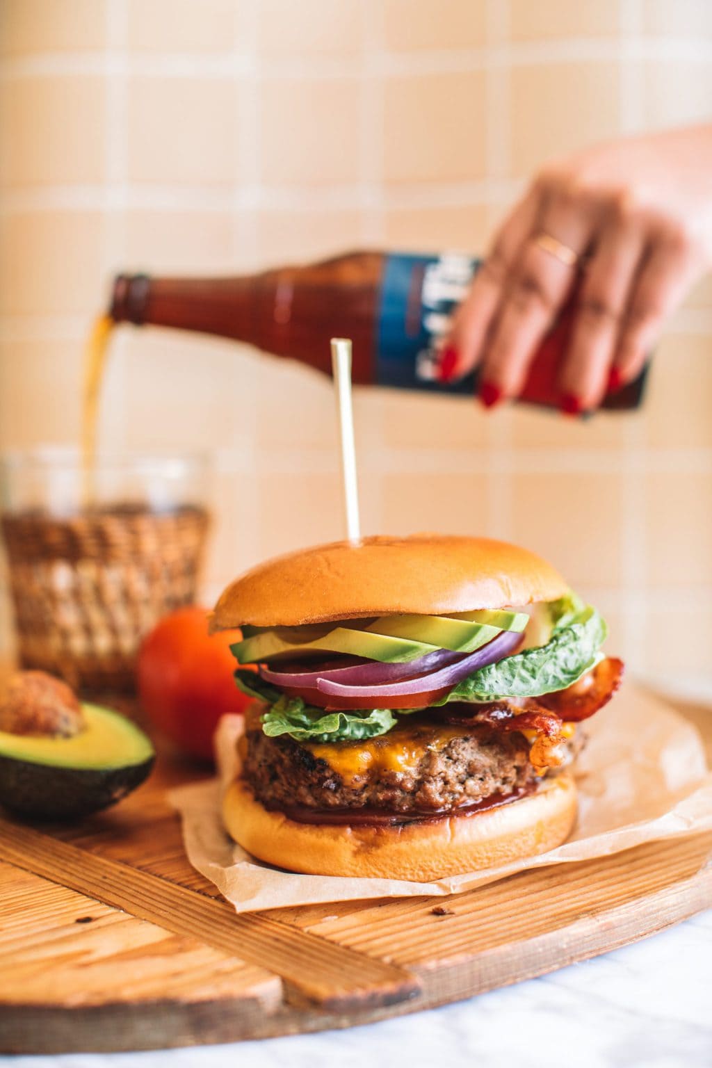 An avocado bacon burger served with a cold beer.