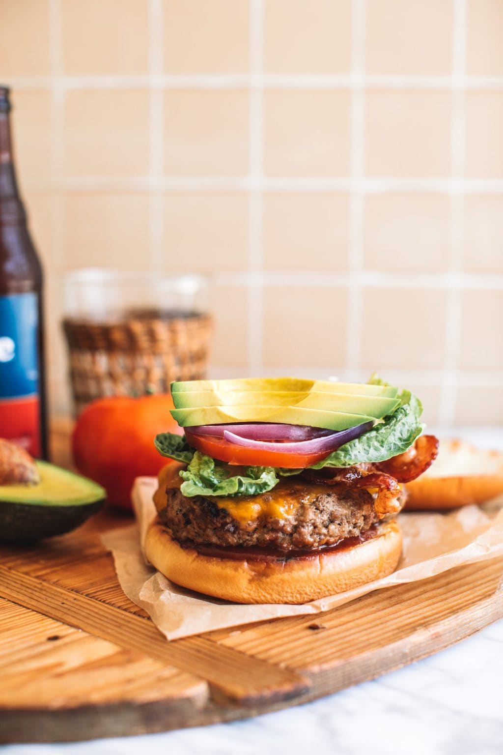 An avocado bacon burger topped with thick slices of avocado.