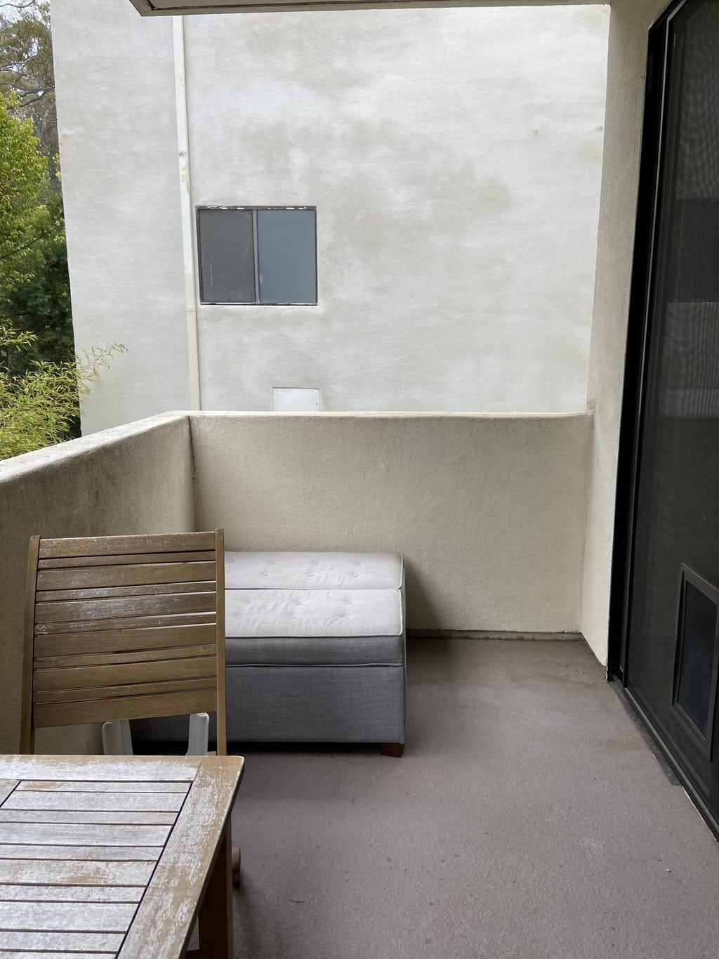 The before side of the lounge area of the patio with a small grey bench. 