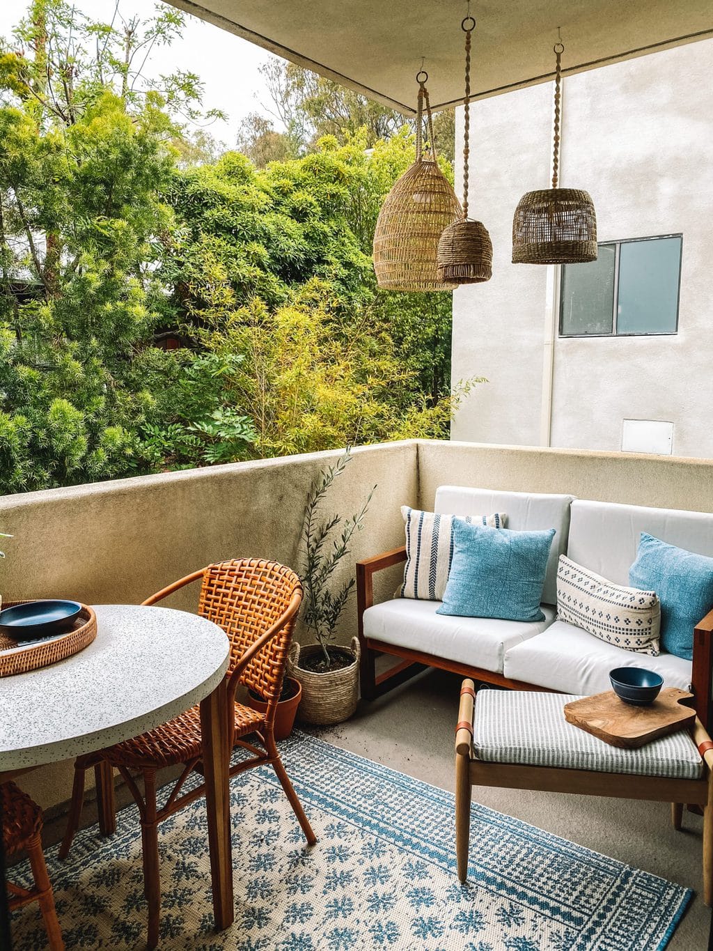 Lounge side of a patio makeover with basket lanterns, a love seat and foot stool. 