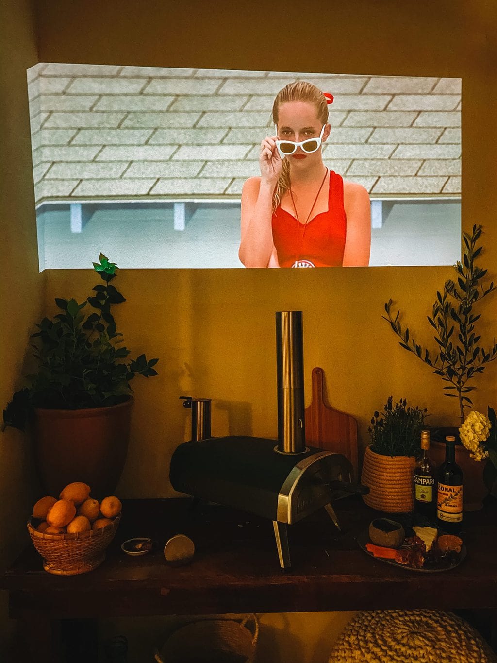 A blank wall with a movie being projected on it in the evening. 