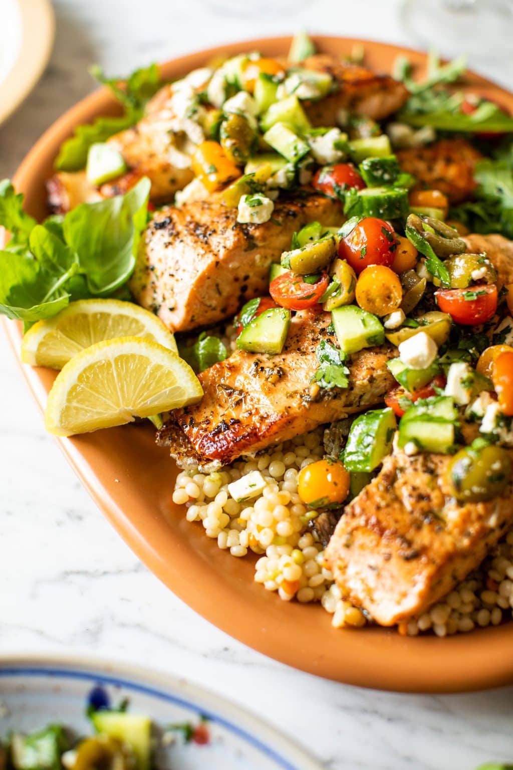 baked lemon salmon with Mediterranean topper on large orange platter