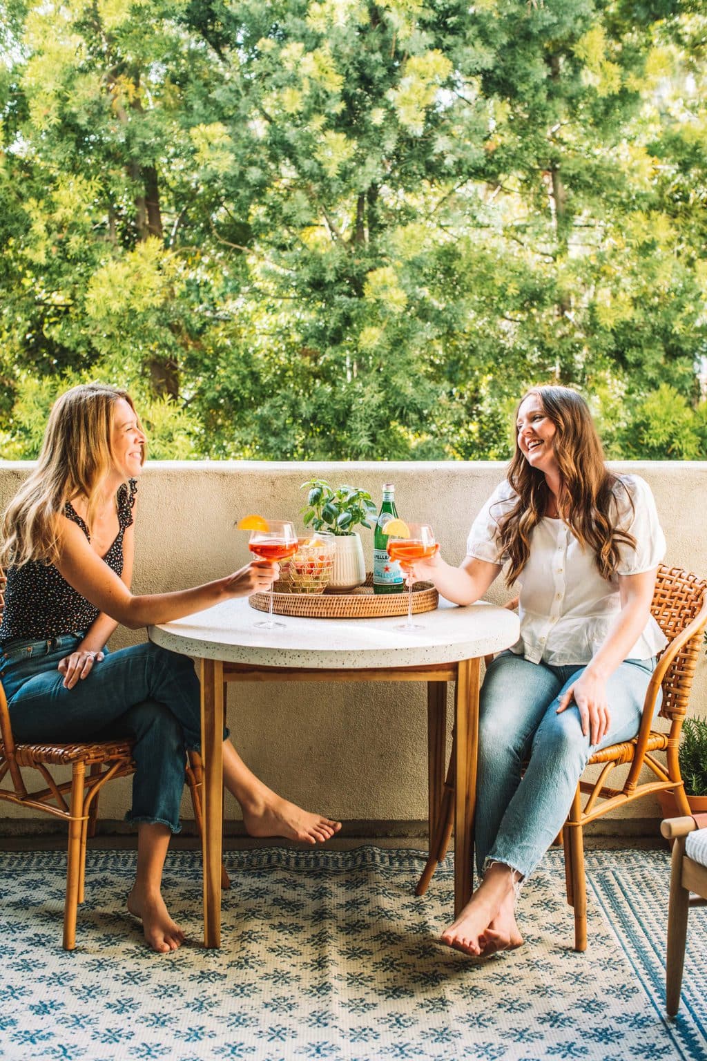 Two girls enjoying a cocktail on an outdoor dining table set. 