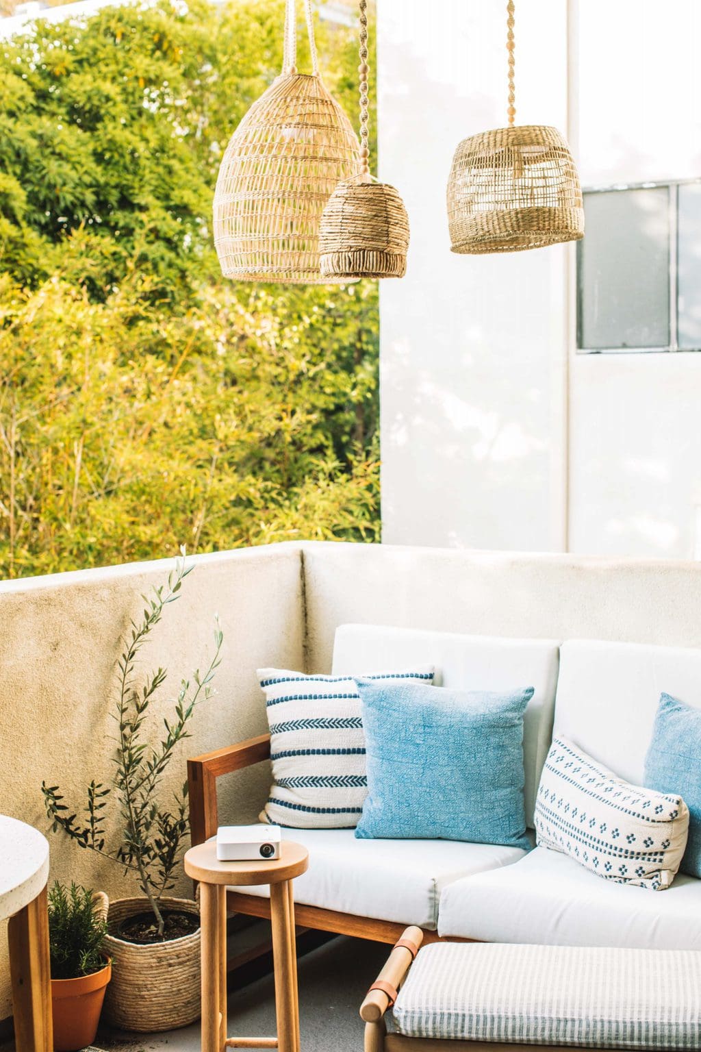 Lanterns hanging over an outdoor love seat with a small stool with a projector on it. 