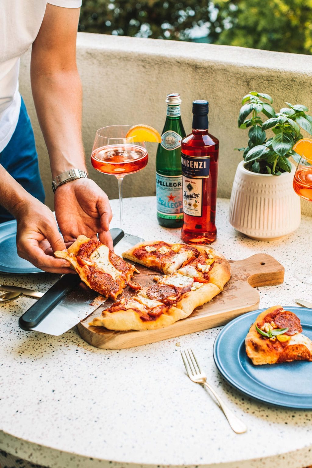 A slice of pizza being pulled off of a wooden cutting board. 