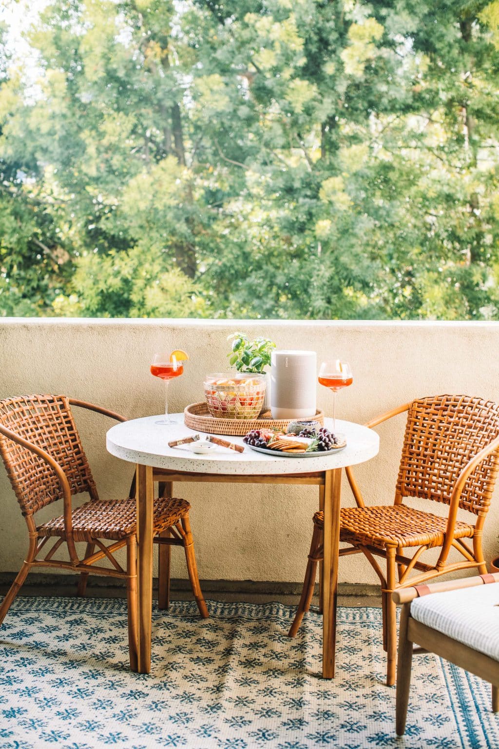 A circle dining table with two wicker chairs on top of a blue and white rug. 