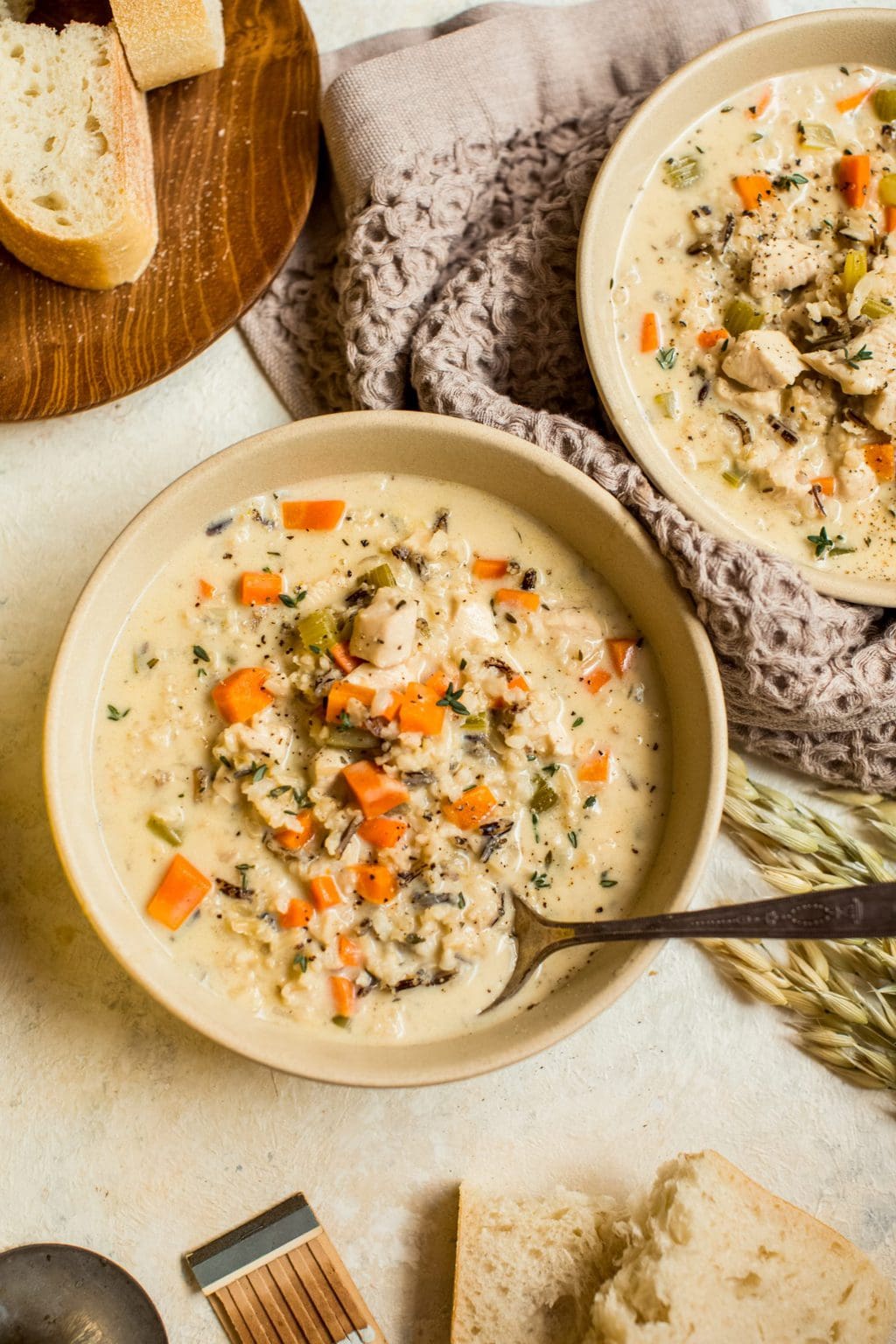 creamy chicken and rice soup in two beige bowls with spoons