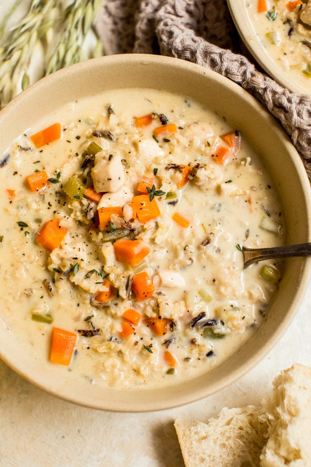 creamy chicken and rice soup in a beige bowl with a purple napkin