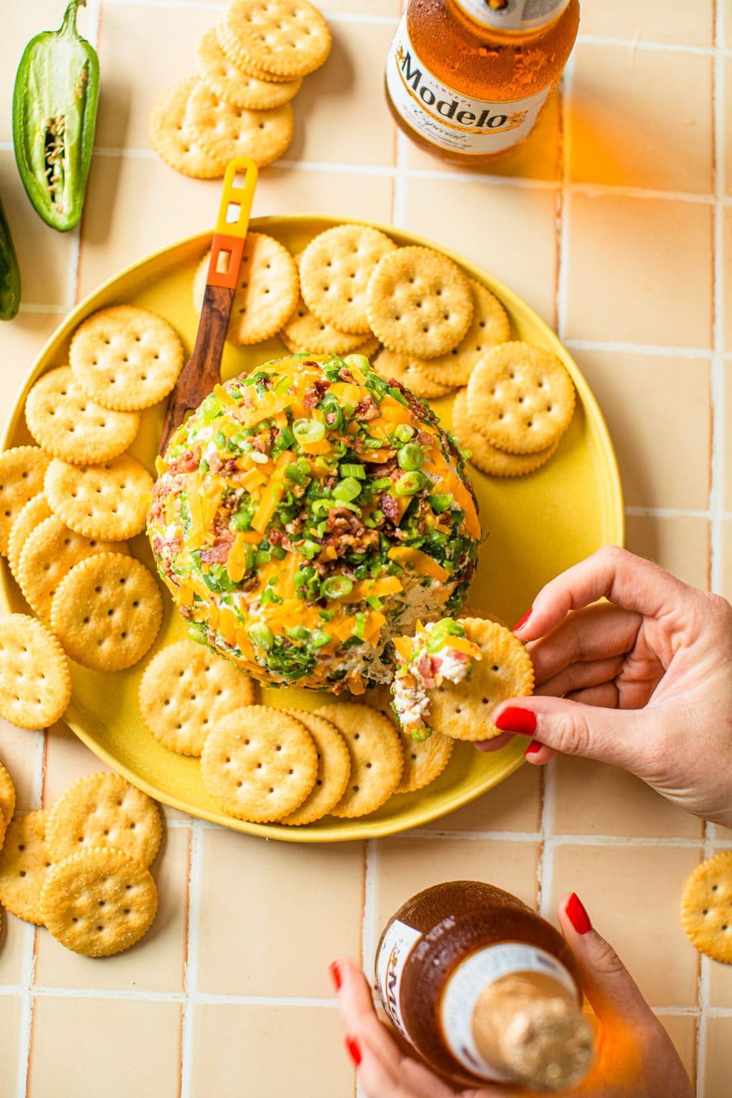 hand dipping cracker in jalapeno popper cheese ball