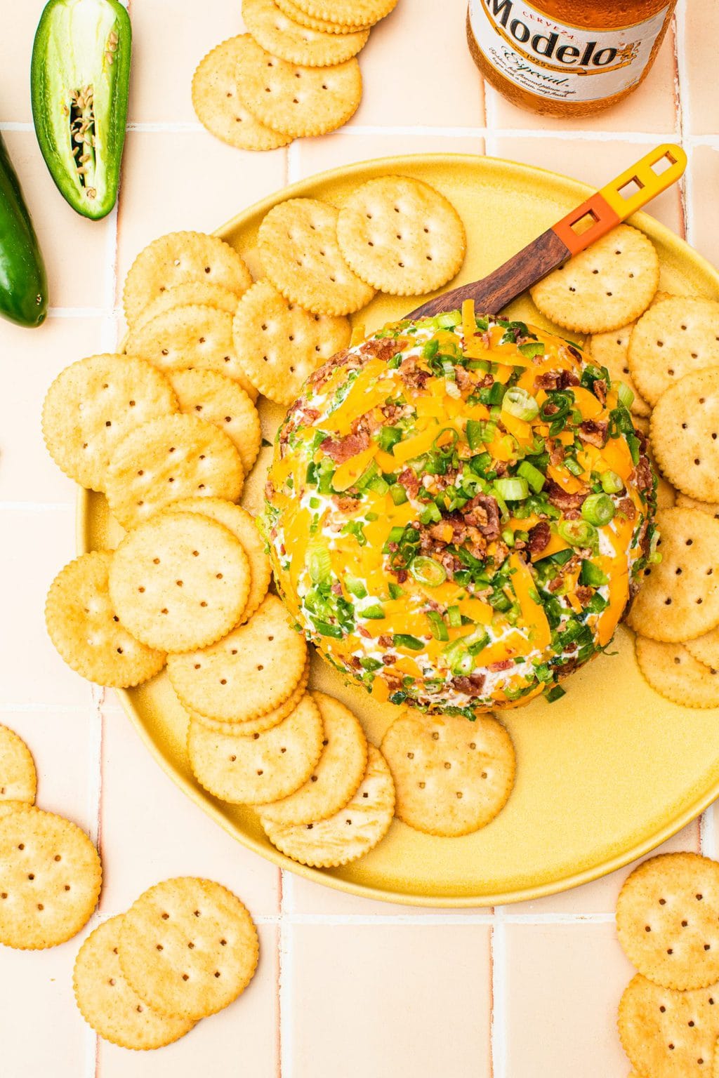 jalapeno cheese ball on yellow platter with butter crackers