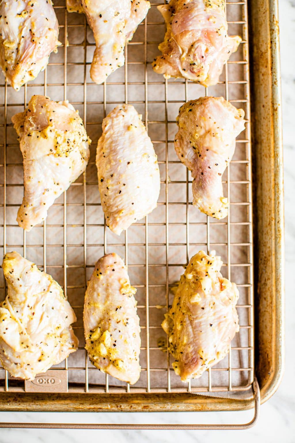 raw chicken wings on wire rack over baking sheet