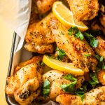 baked chicken wings with lemon wedges and parsley