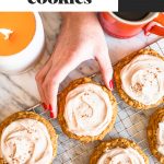 hand grabbing giant pumpkin oat cookie with icing