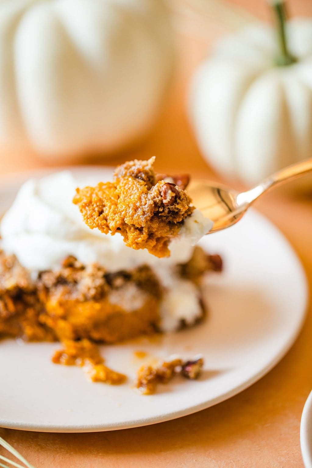 a fork full of pumpkin dump cake topped with a little whip cream