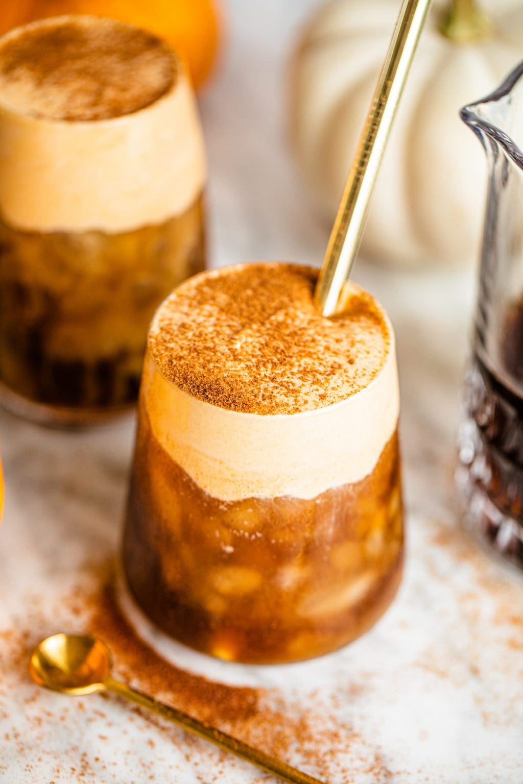 pumpkin cold foam iced coffee in glass with gold straw