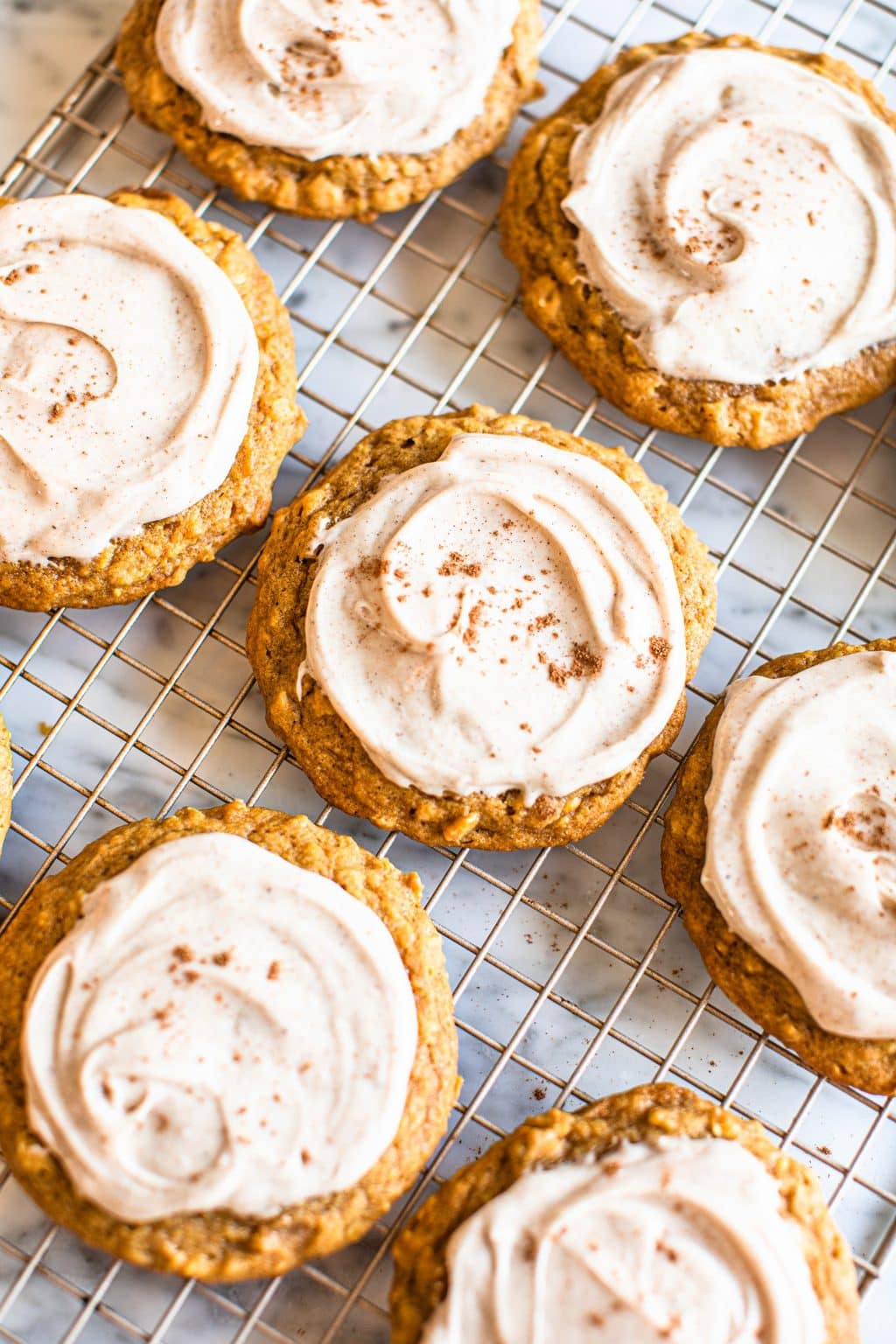 pumpkin oat cookies with icing on cooling rack