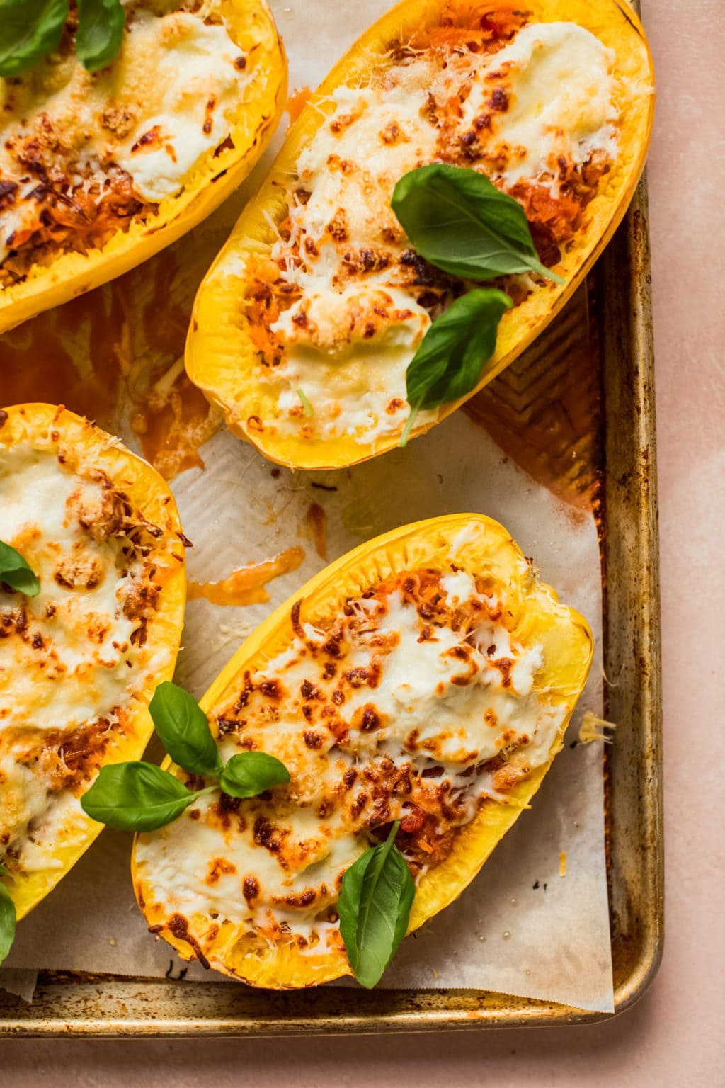 spaghetti squash halves filled with meat, sauce and cheese on baking sheet