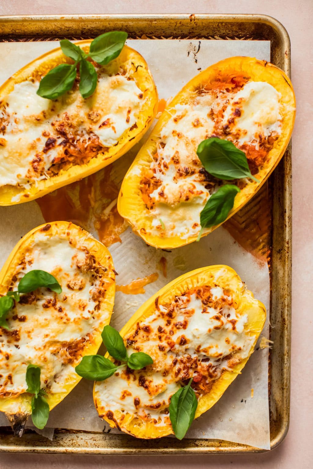 spaghetti squash halves filled with meat, sauce and cheese on baking sheet