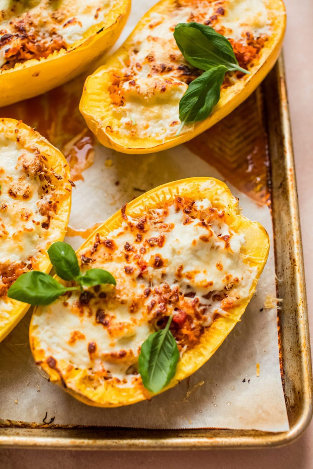 spaghetti squash halves filled with meat, sauce and cheese on baking sheet