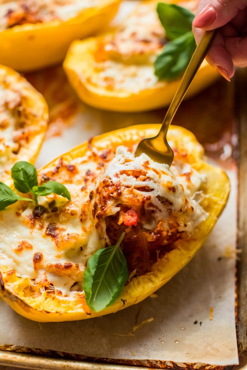 fork digging into spaghetti squash half filled with meat, sauce and cheese