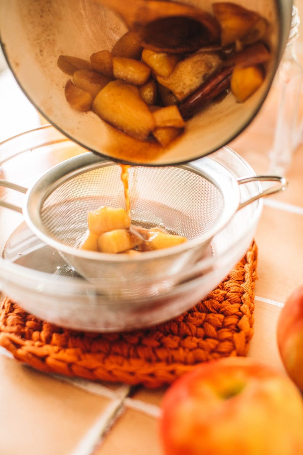 straining apple simple syrup into glass bowl