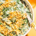 best creamed spinach with cracker topping in white bowl with spoon