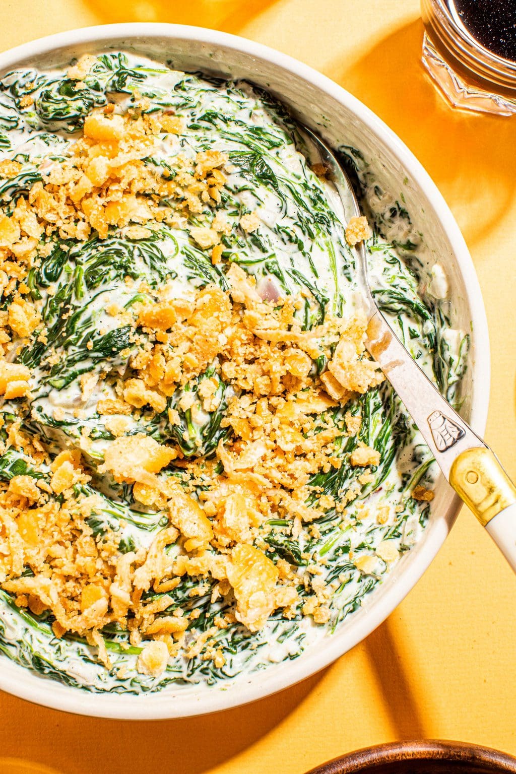 best creamed spinach with cracker topping in white bowl with spoon