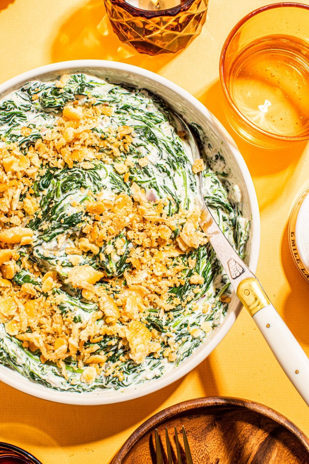 best creamed spinach with cracker topping in white bowl with spoon