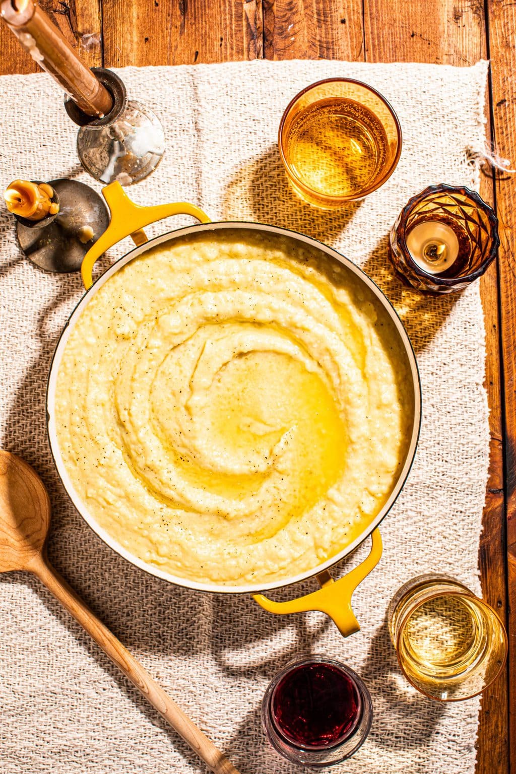 homemade garlic butter mashed potatoes in yellow pot with glasses surrounding