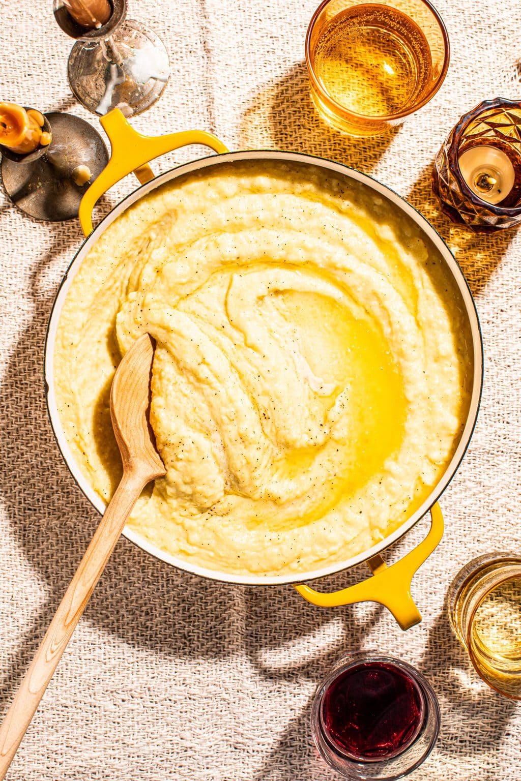 creamy garlic butter mashed potatoes in yellow pot with wooden spoon