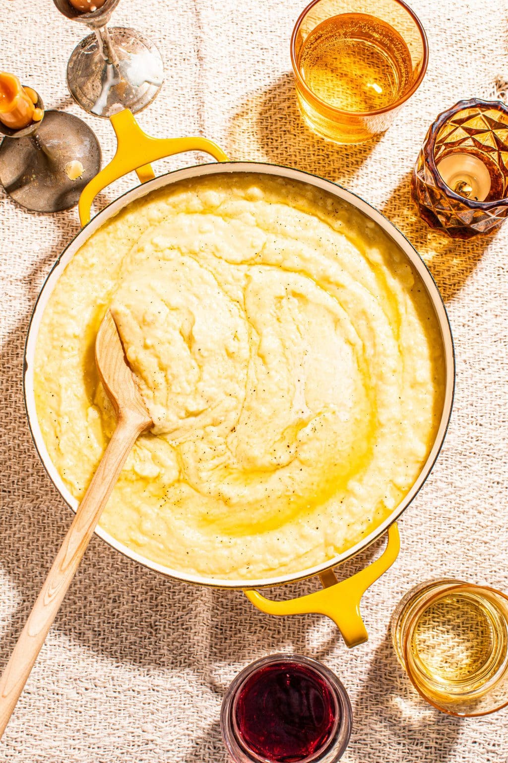 creamy garlic butter mashed potatoes in yellow pot with wooden spoon