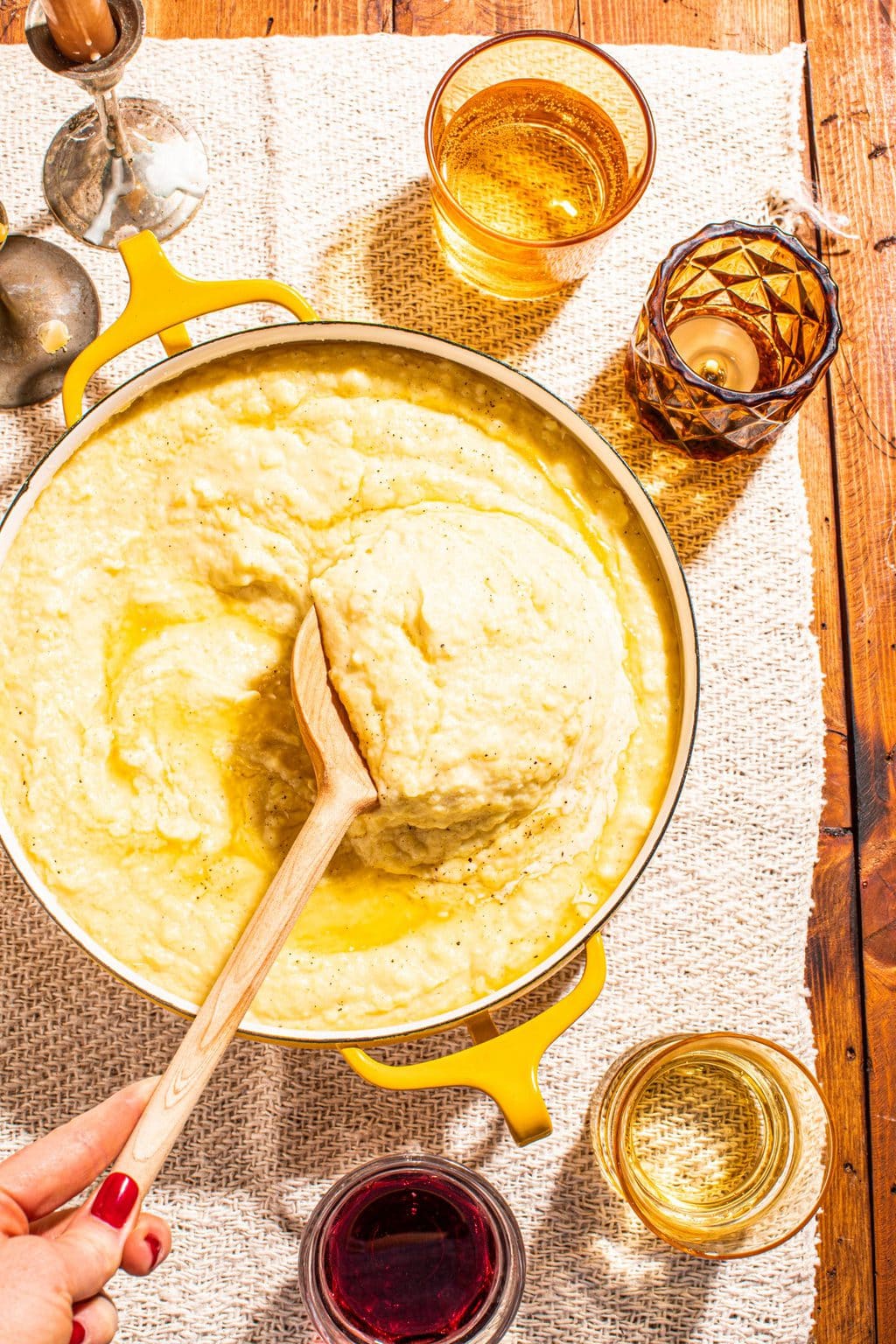 creamy garlic butter mashed potatoes in yellow pot with wooden spoon