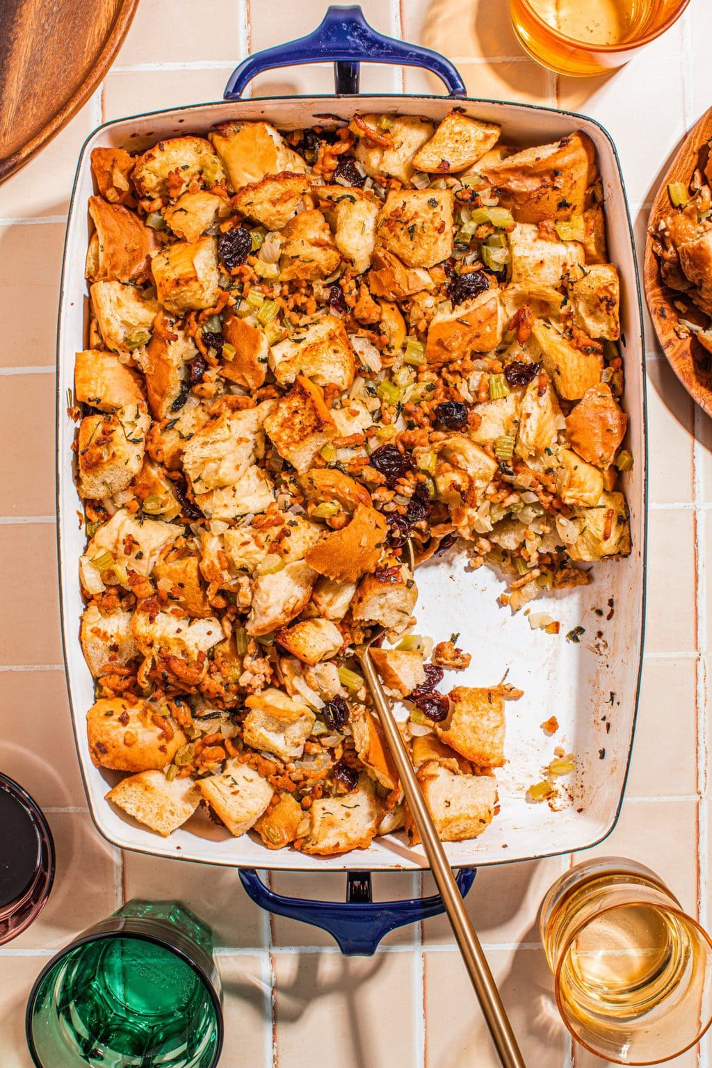 homemade sausage stuffing in white casserole dish with serving spoon