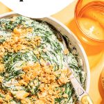 best creamed spinach with cracker topping in white bowl with spoon