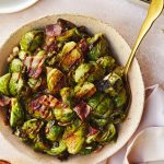 Brussel sprouts served in a pink bowl with a golden serving spoon.