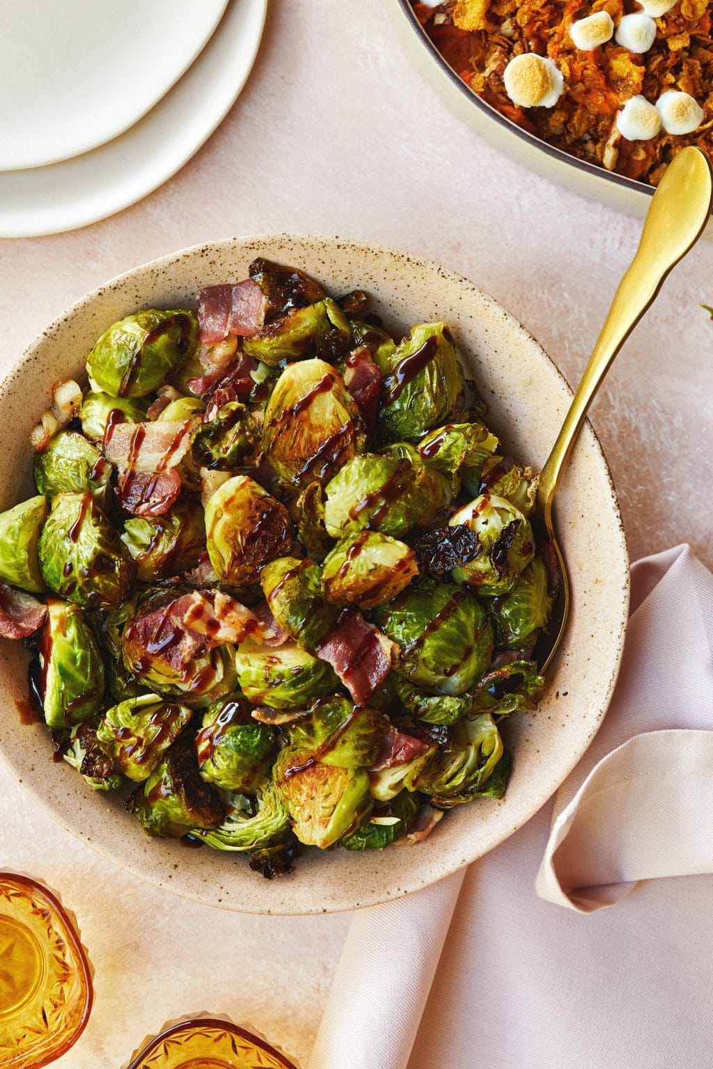 Brussel sprouts served in a pink bowl with a golden serving spoon.