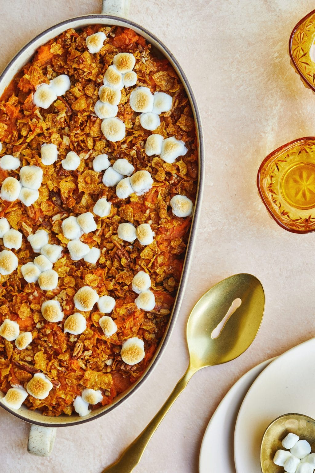 Platter of mashed sweet potatoes with marshmallows and a golden spoon next to the dish. 