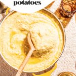 creamy garlic butter mashed potatoes in yellow pot with wooden spoon