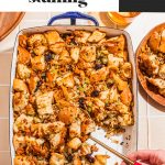 hand scooping out sausage herb stuffing from white baking dish