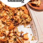 easy sausage stuffing in white baking dish with serving spoon